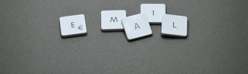 Close-up of the word 'email' formed with letter tiles on a gray surface.